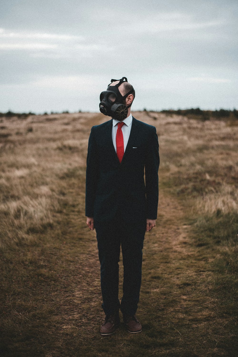 man in black suit standing on brown field during daytime