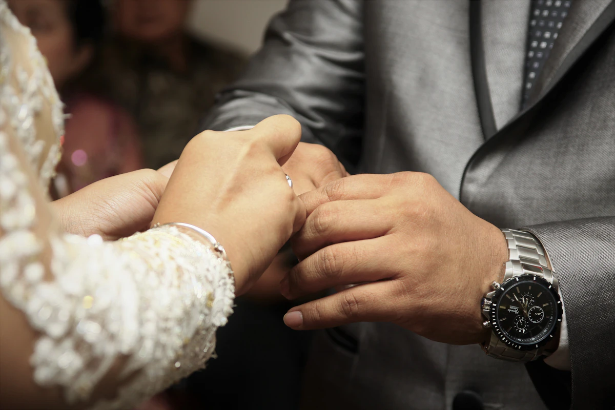 Dua cincin perak di jari tangan pasangan pengantin