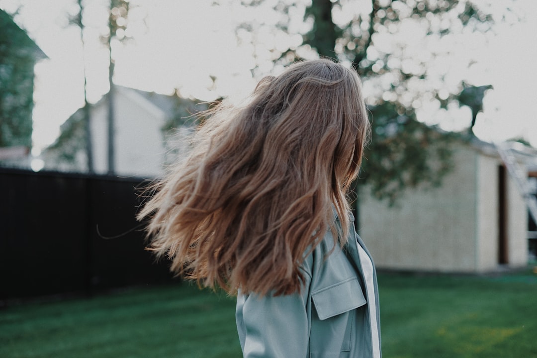 woman in blue denim jacket standing on green grass field during daytime