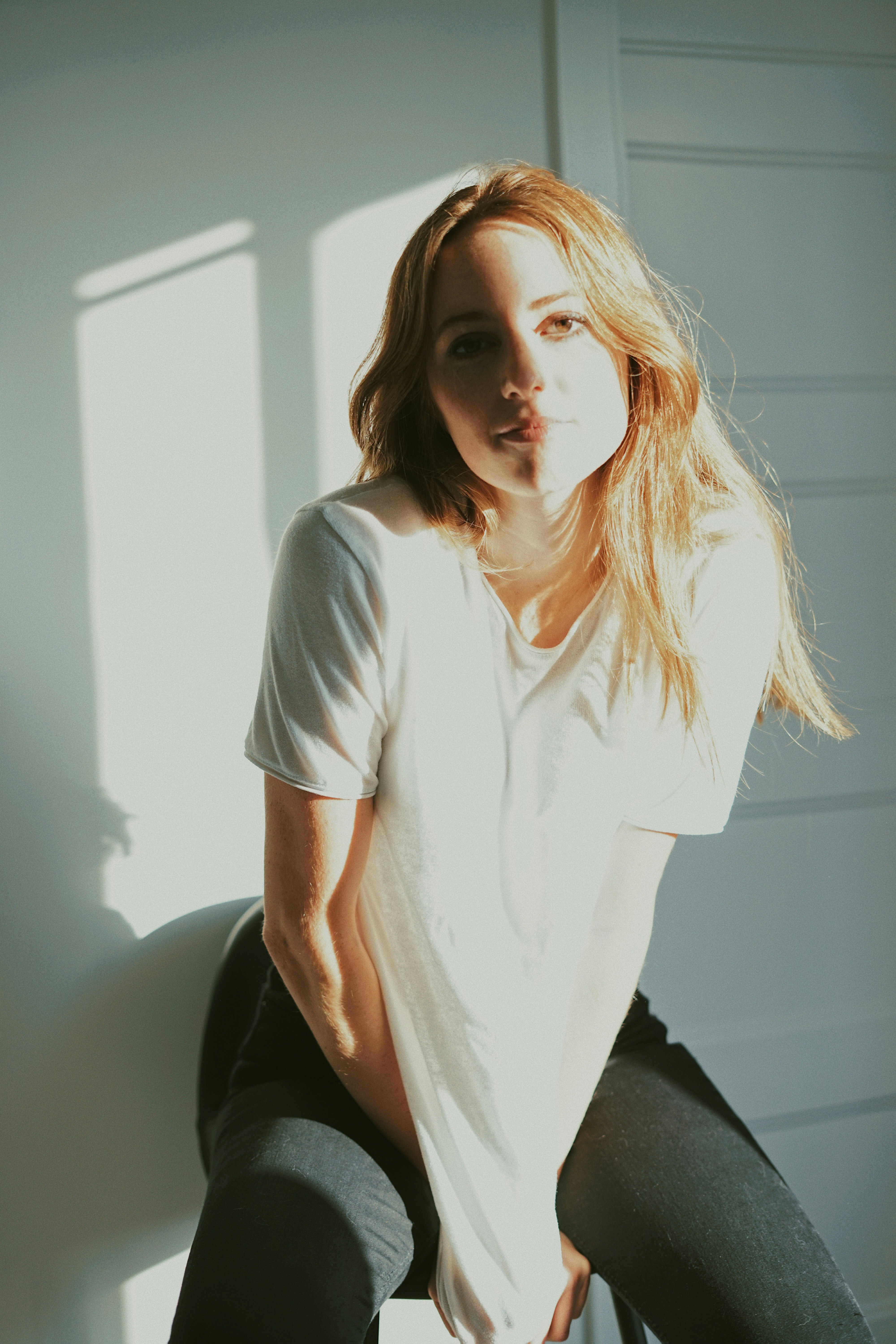 woman in white crew neck t-shirt and black pants sitting on black chair