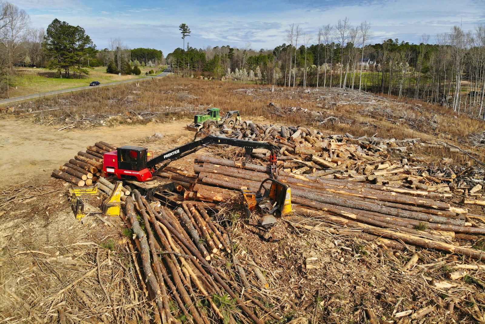Heavy equipment stacking cut timber on a partially cleared site