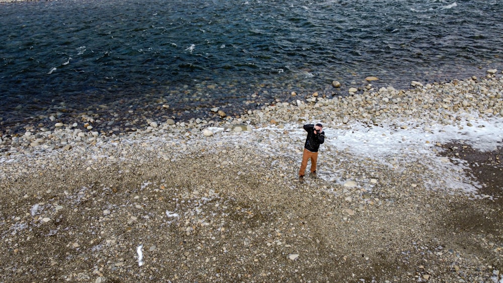 person in black shorts walking on rocky shore during daytime