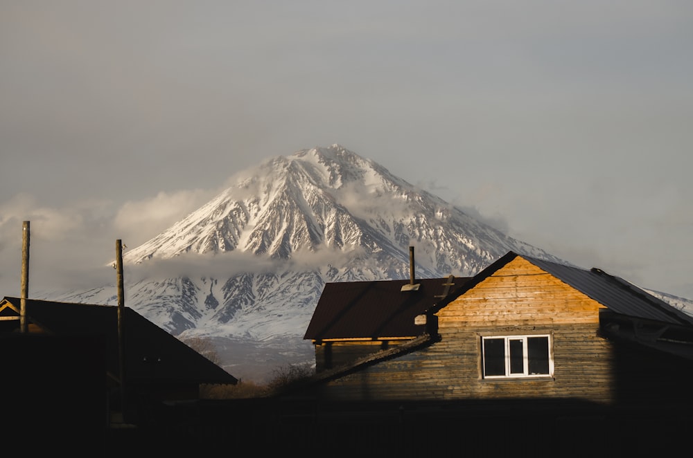 brown wooden house near snow covered mountain during daytime