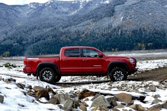 red crew cab pickup truck on rocky ground