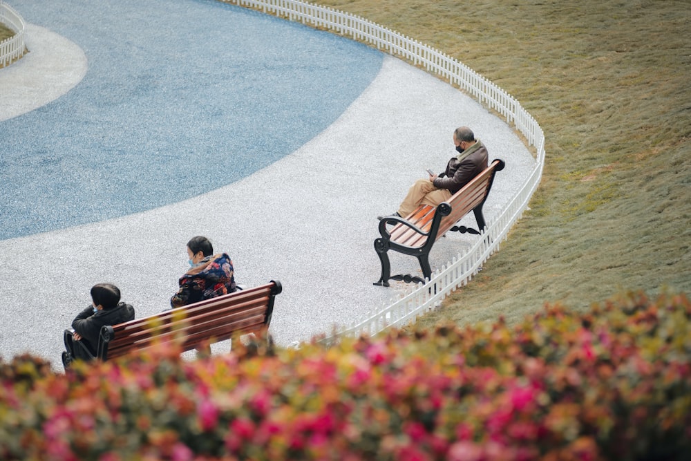 2 women sitting on brown wooden bench during daytime