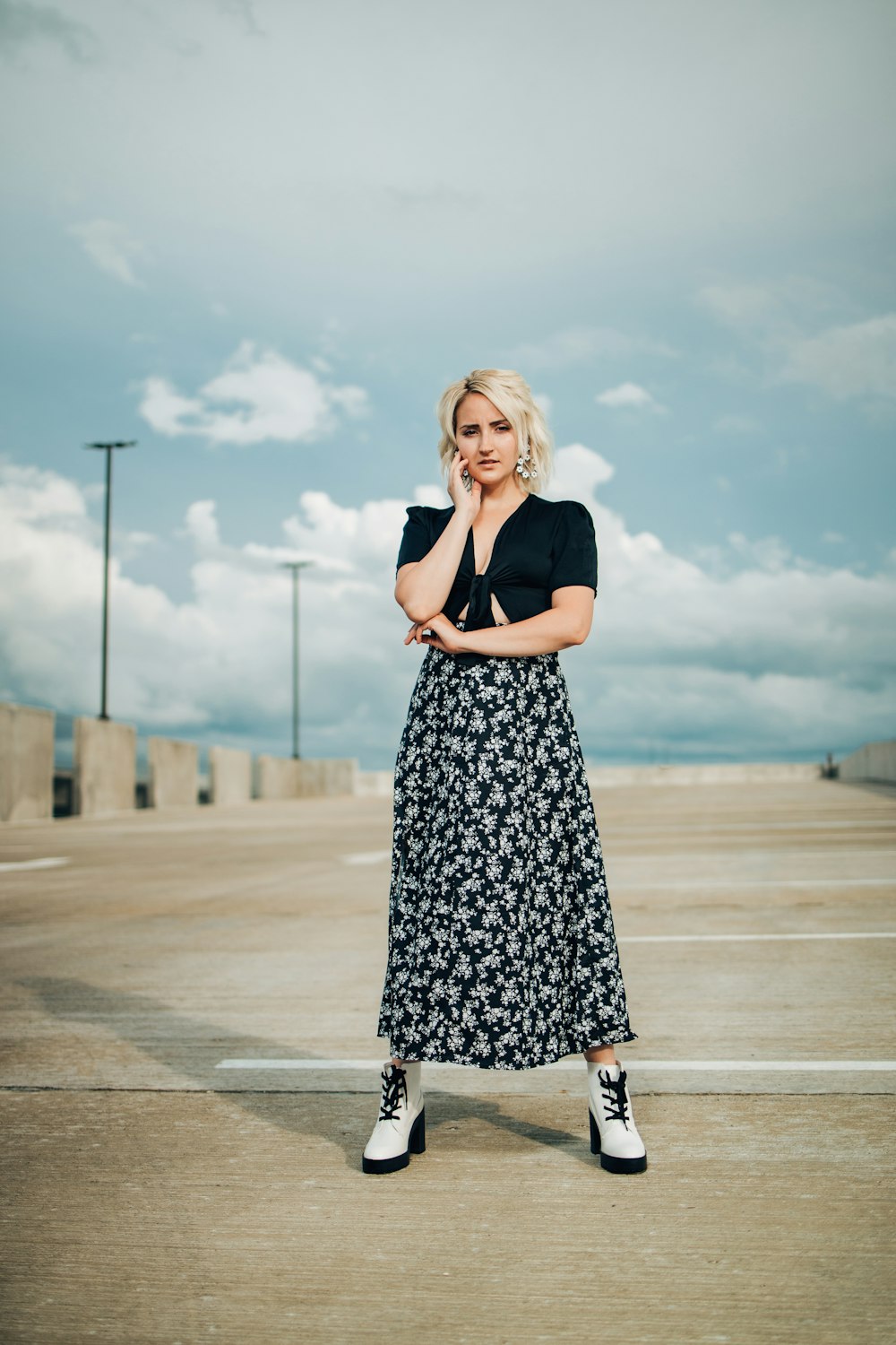 woman in black sleeveless dress standing on gray concrete road during daytime