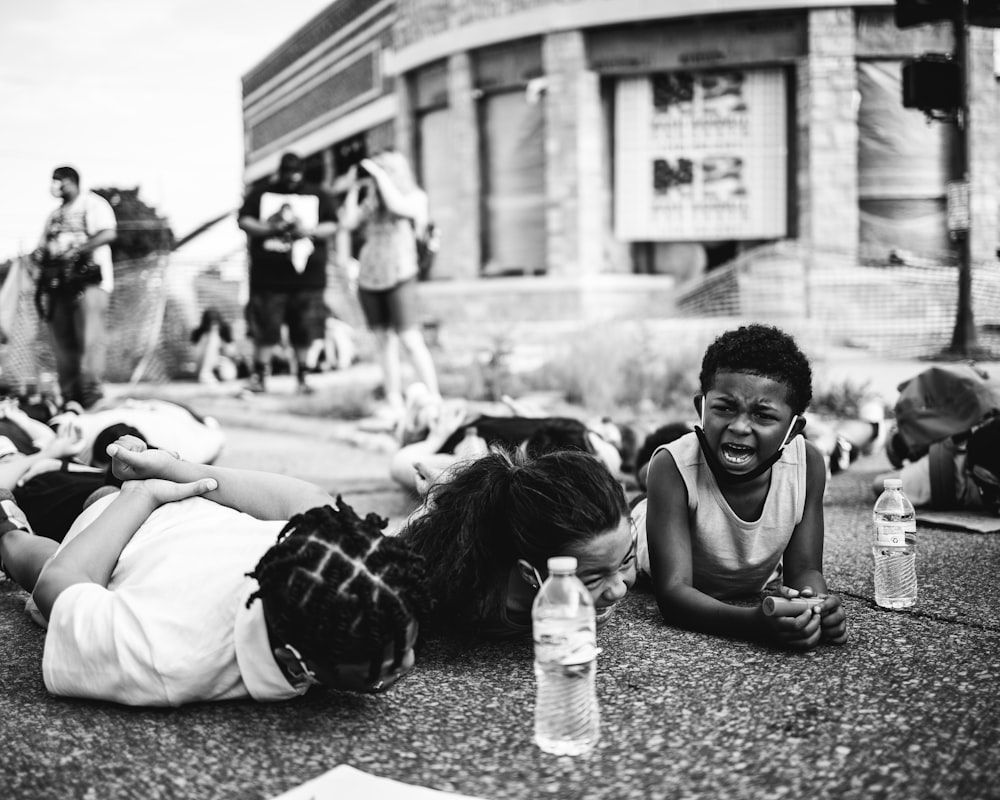 grayscale photo of man and woman sitting on ground