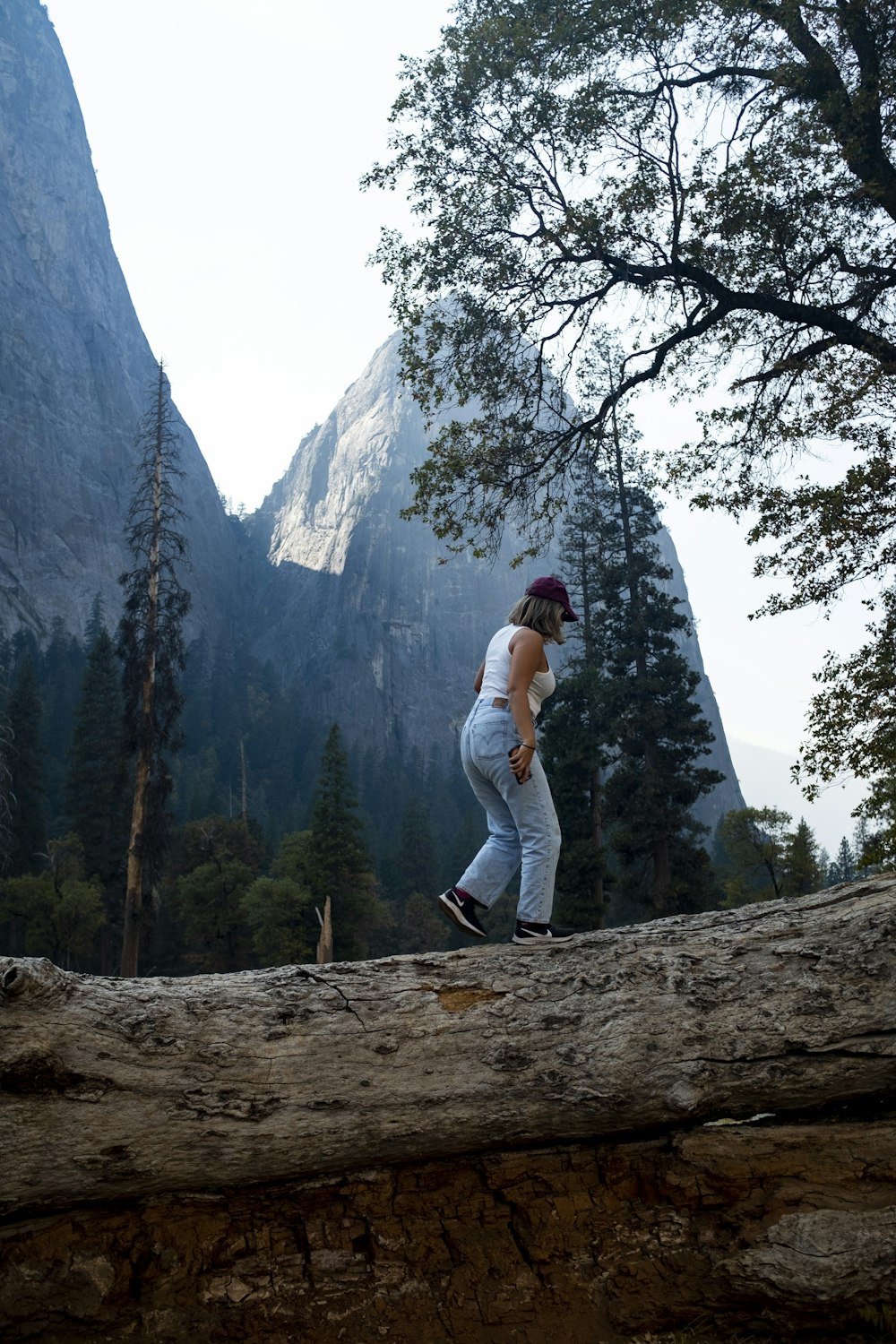 Femme en chemise blanche à manches longues et pantalon blanc debout sur la roche brune pendant la journée