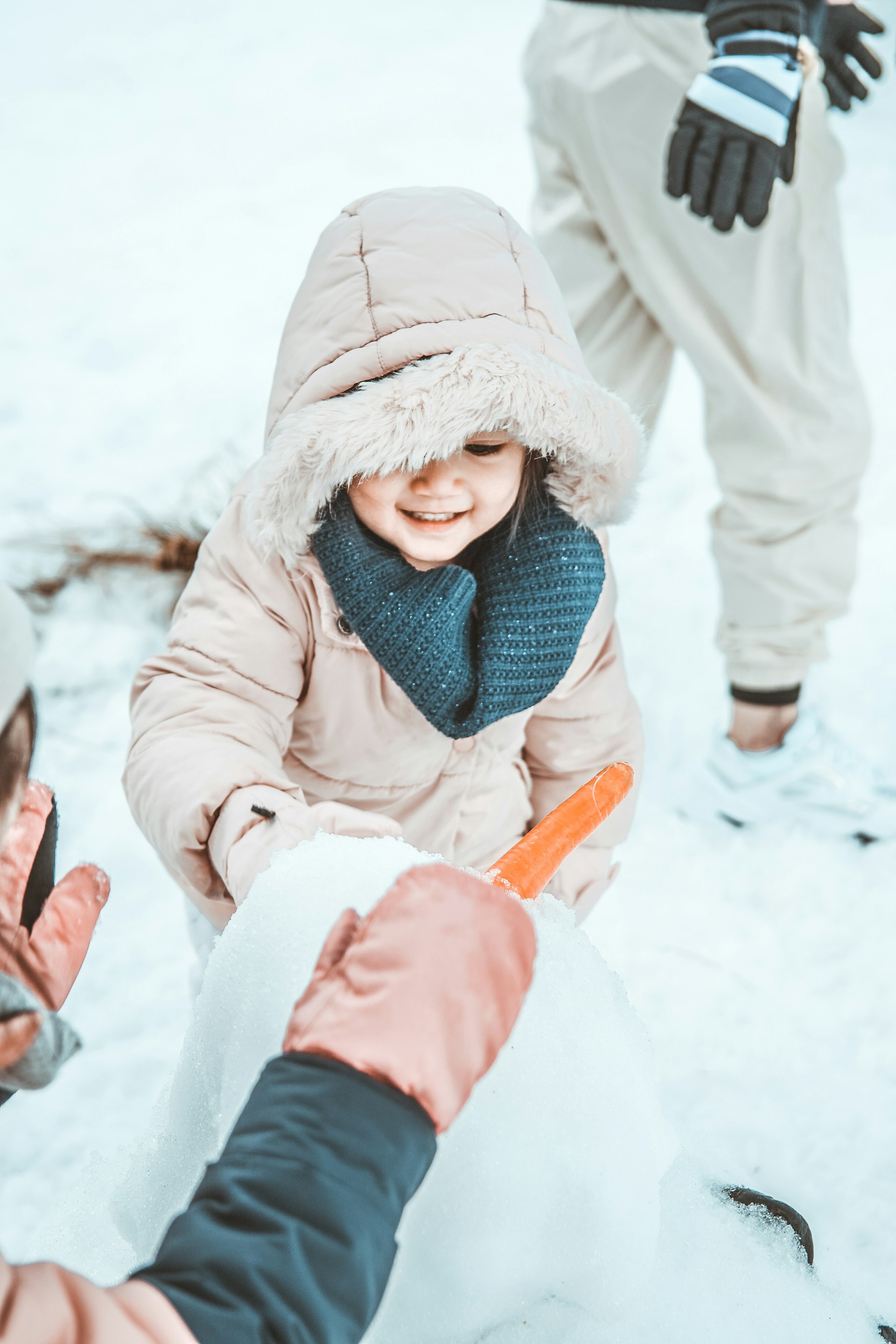 A child bundled up in a warm winter coat playing in the snow with a bright smile