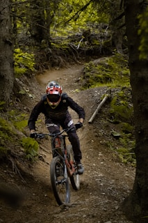 man in black jacket riding red and white mountain bike