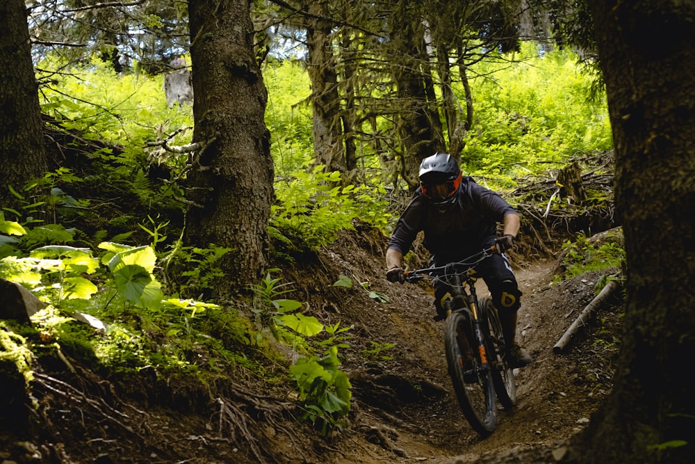 man in black helmet riding bicycle in forest during daytime