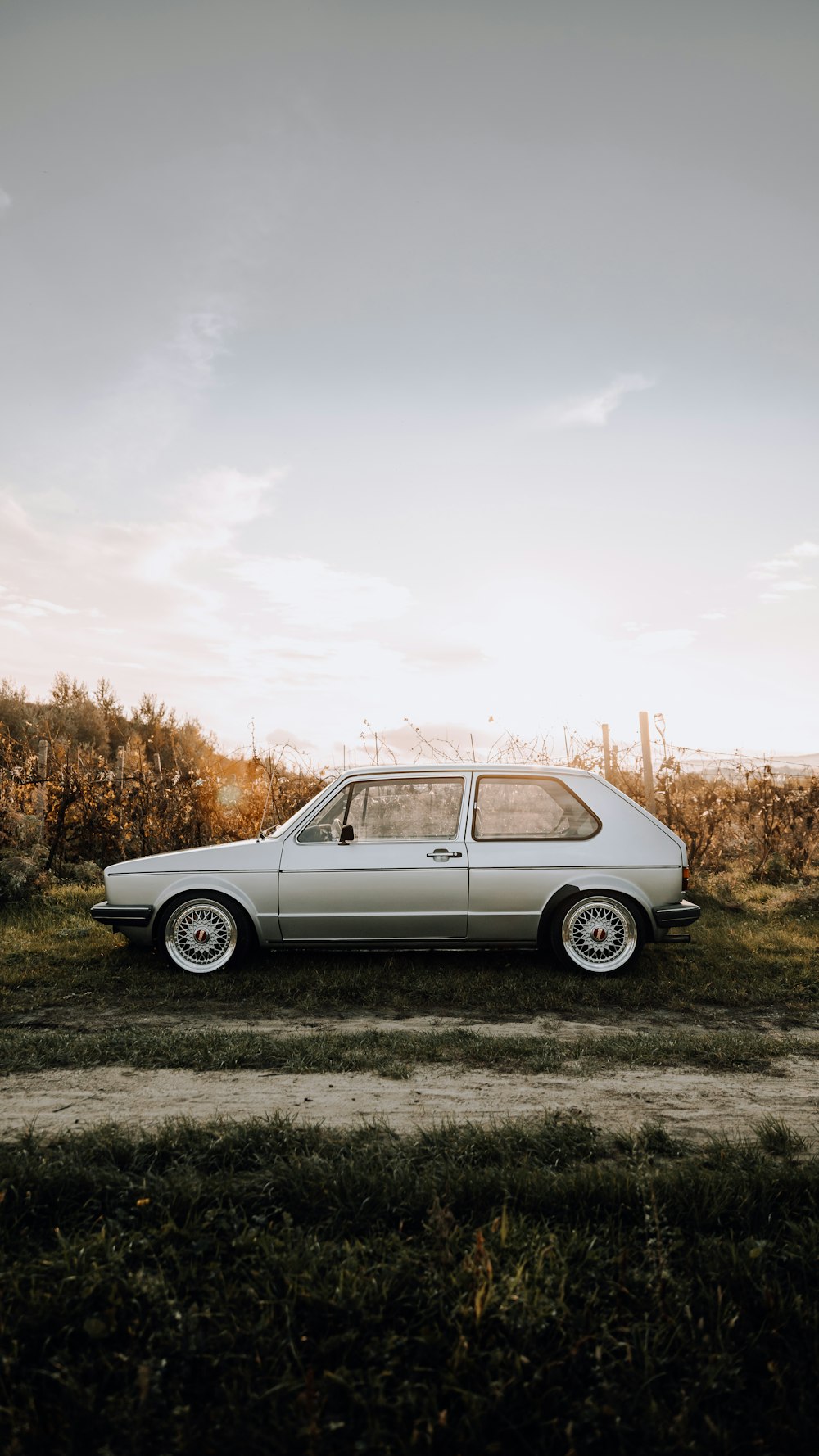 white station wagon on green grass field under white clouds during daytime