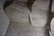 An interior ceiling made of concrete, featuring angular and geometric shapes with visible wood grain textures from the mold. The surface appears worn and has a grayish tone with variations due to shadows and lighting.