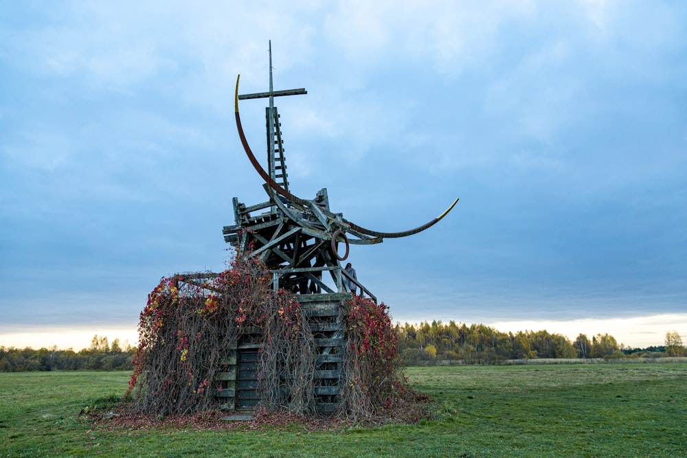 brown wooden windmill on green grass field under blue sky during daytime