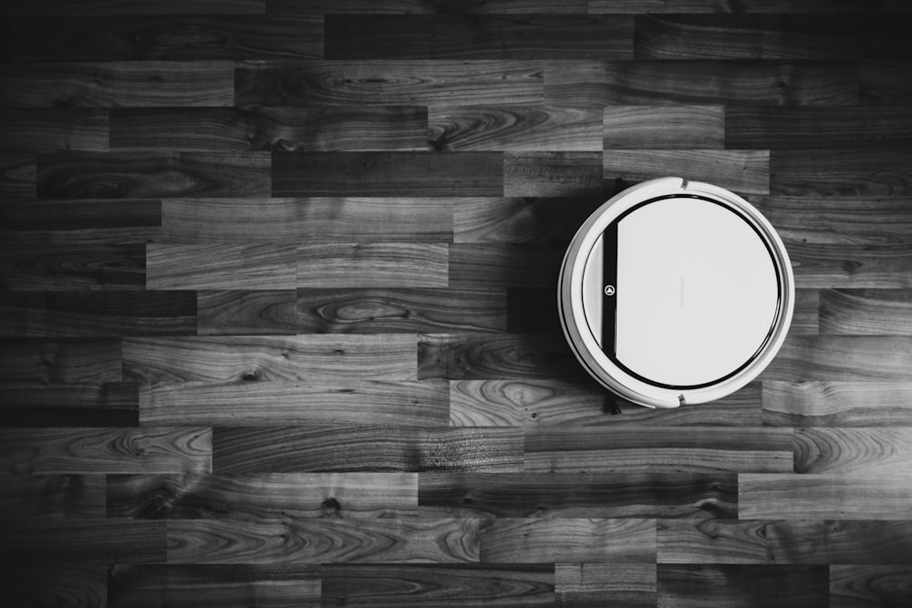 grayscale photo of round frame on wooden floor