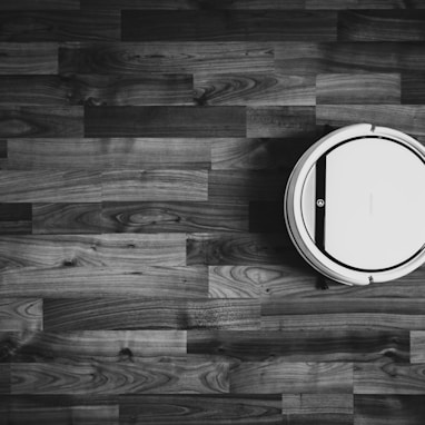 grayscale photo of round frame on wooden floor