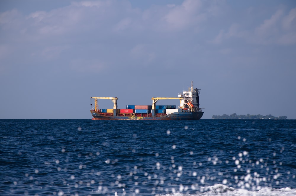 cargo ship on sea under cloudy sky during daytime