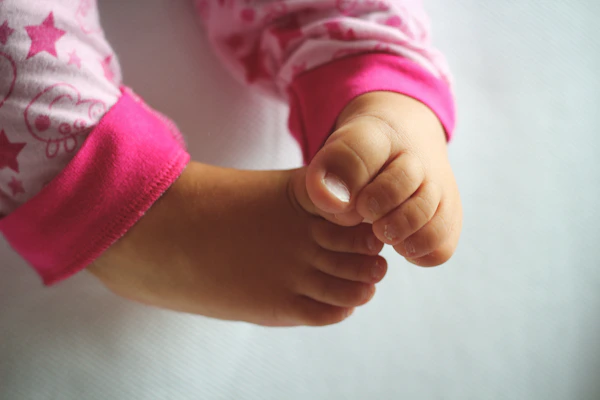 Close-up of a baby's feet wearing soft pastel pink shoes with gentle textures.