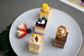 An assortment of colorful cakes with fresh fruit toppings displayed on a white plate