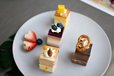 A colorful display of healthy cakes including blueberry lemon and mango coconut slices on a ceramic plate.