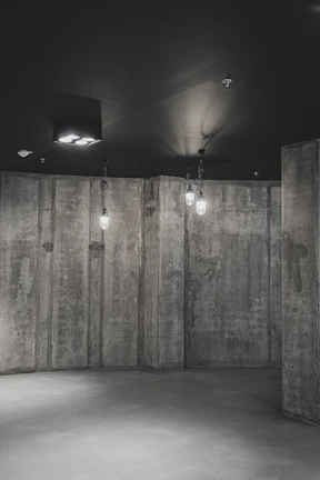 Warm golden-orange lit interior featuring minimalist furniture and raw concrete walls.