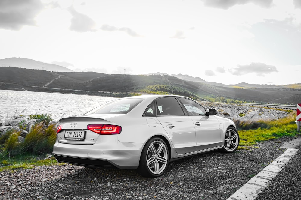 BMW M 3 coupé blanc sur sol noir près d’un plan d’eau pendant la journée