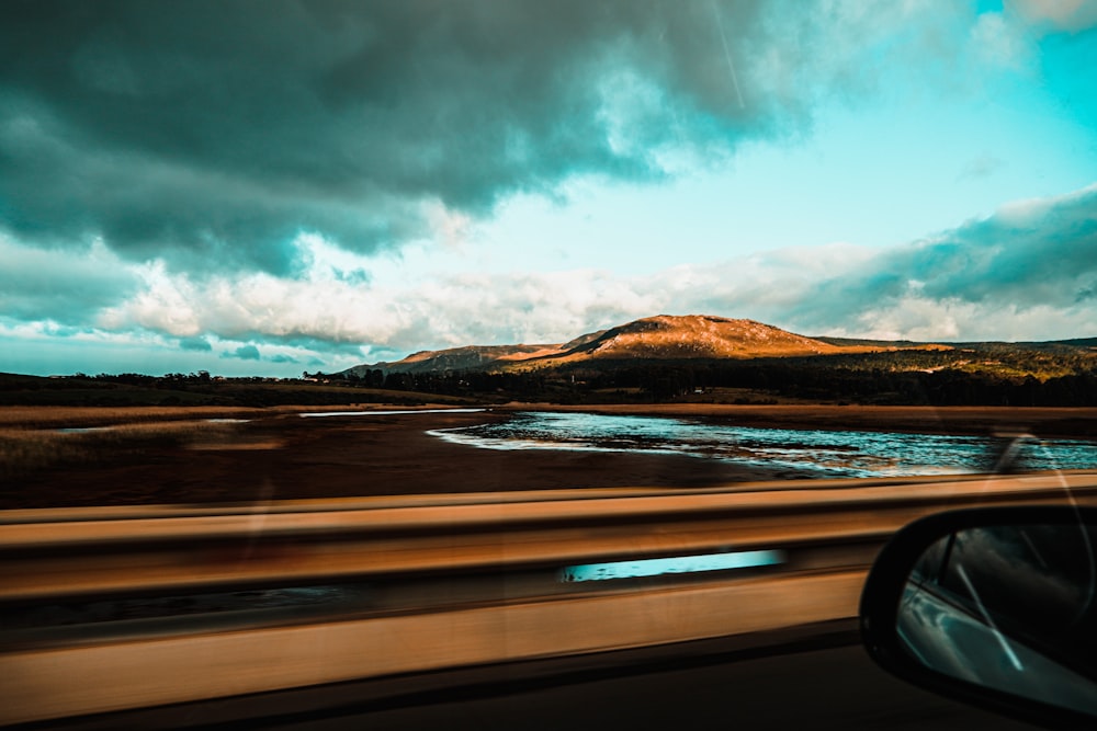 body of water near mountain under cloudy sky during daytime