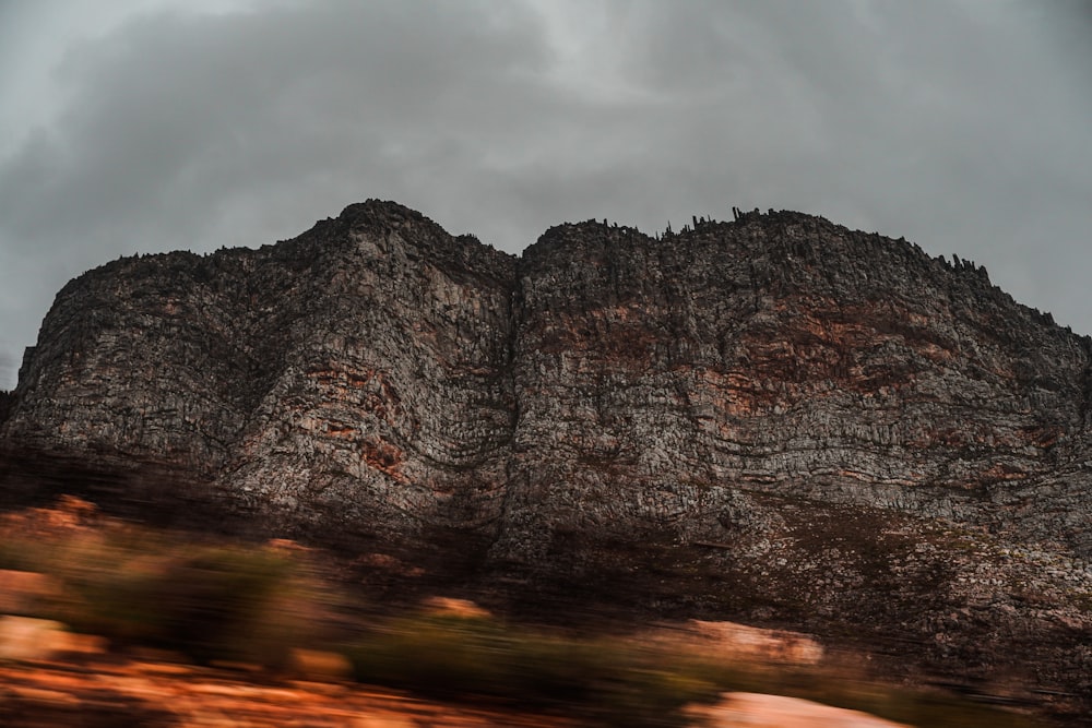 Montagne rocheuse brune sous des nuages gris au coucher du soleil