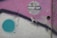 An abstract piece of street art featuring a mix of colors and shapes. The artwork includes a large turquoise circle, a zigzag arrow, and a word 'STREET ART' written in white within a circle. The background blends shades of purple, grey, and beige with textured and weathered surfaces.