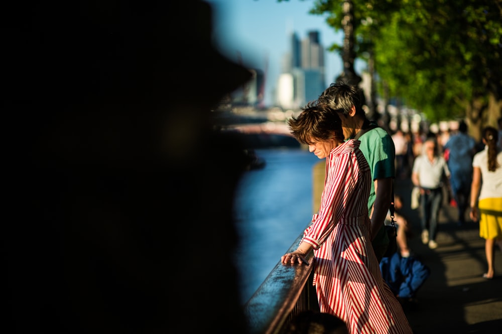 woman in red and white striped dress walking on sidewalk during night time