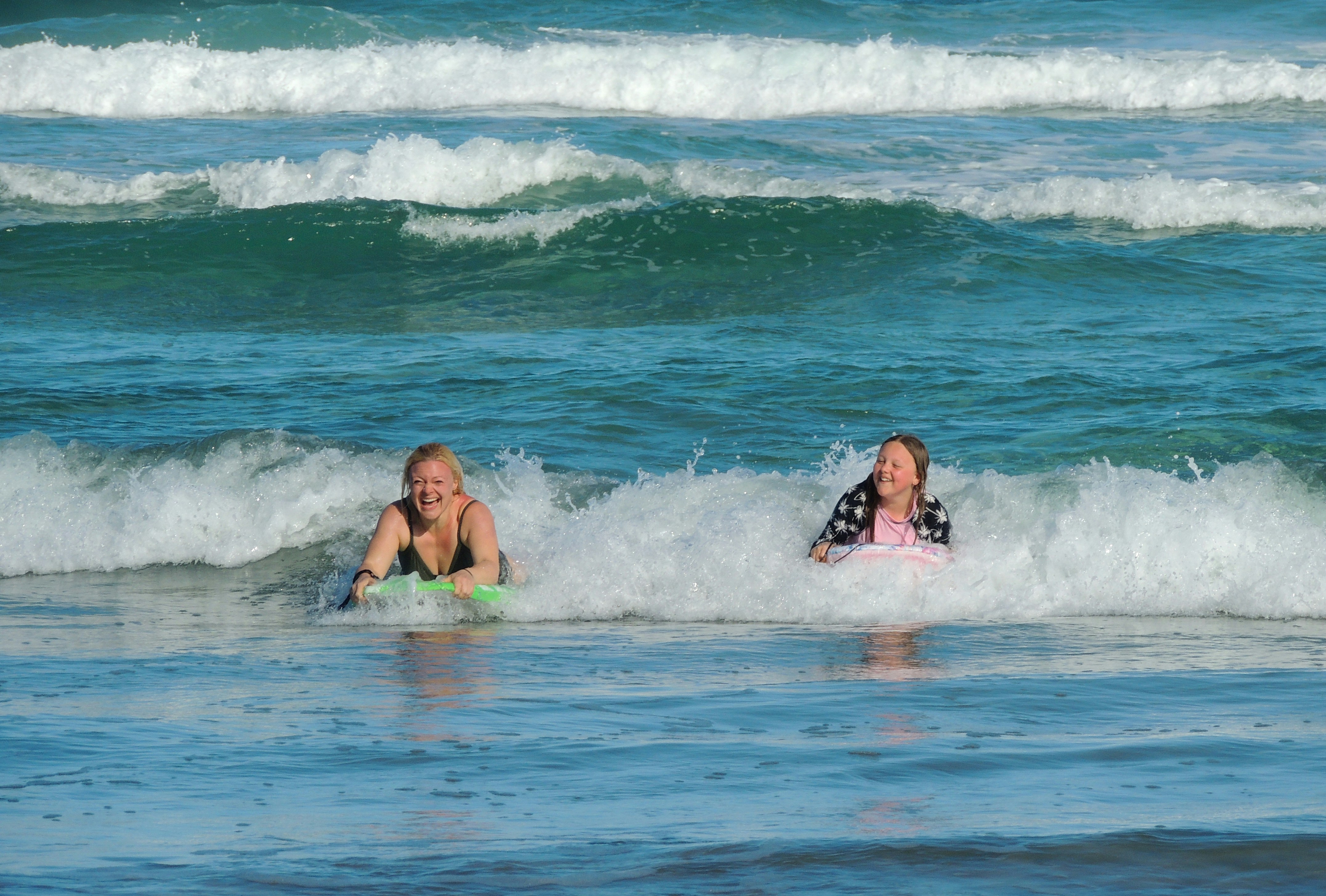 2 women in green bikini swimming on beach during daytime