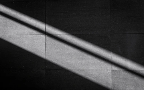 A medium square tile showing abstract shadows and light interplay in monochrome.