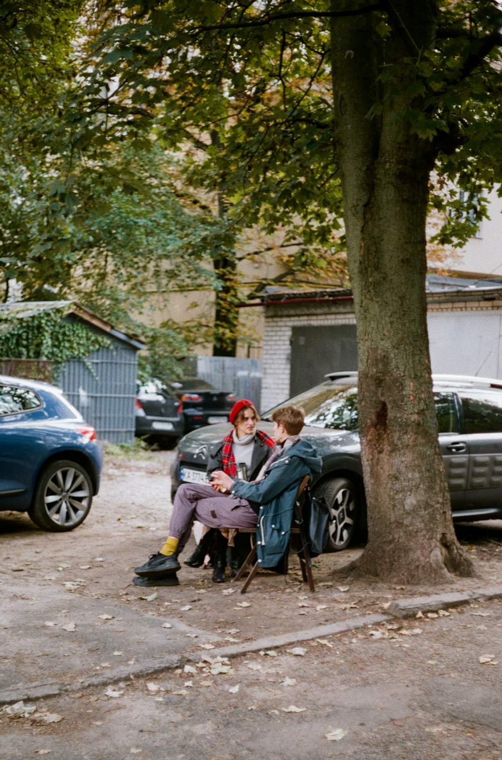 man in white shirt sitting on black bench beside blue car during daytime