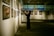 An art gallery with several framed paintings displayed on the walls. A person stands in front of the artwork, seemingly taking pictures or observing closely. The lighting is soft and focused on the paintings, creating a serene and contemplative atmosphere.