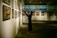 An art gallery with several framed paintings displayed on the walls. A person stands in front of the artwork, seemingly taking pictures or observing closely. The lighting is soft and focused on the paintings, creating a serene and contemplative atmosphere.
