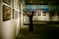 An art gallery with several framed paintings displayed on the walls. A person stands in front of the artwork, seemingly taking pictures or observing closely. The lighting is soft and focused on the paintings, creating a serene and contemplative atmosphere.
