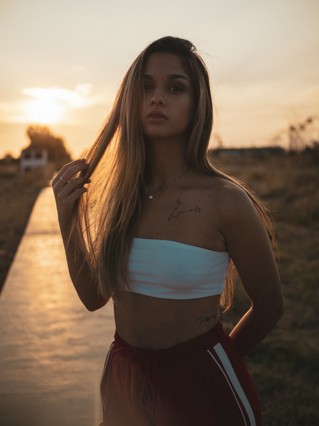 woman in white crop top and red skirt standing on beach during sunset