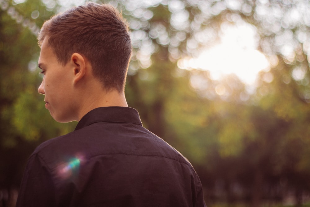 man in black shirt looking at the trees during daytime