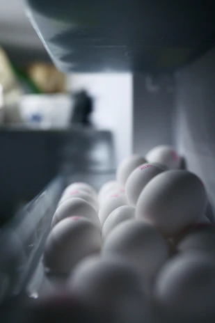 Close-up of fresh eggs packed in industrial 180-count boxes with clear branding in a refrigerated environment.