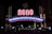 A prominent illuminated archway with the word 'RENO' in bright red letters and the phrase 'THE BIGGEST LITTLE CITY IN THE WORLD' beneath it. Surrounding the arch are various lights and neon signs in a nighttime urban setting.
