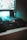 A computer setup featuring a mechanical gaming mouse with illuminated accents on a black mouse pad. The mouse is positioned next to a keyboard, and a monitor displays a blurry, colorful background. Ambient teal lighting creates a futuristic and gaming-themed atmosphere.