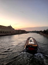 Luxury boat cruising along the Tagus River with Lisbon skyline at sunset.
