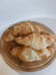 Close-up of golden, flaky croissants stacked on a rustic wooden board