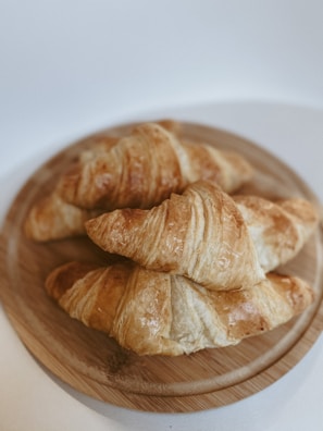 Close-up of golden croissants stacked on a rustic wooden board.