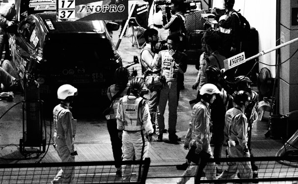 A team of drivers discussing strategies in a pit area.