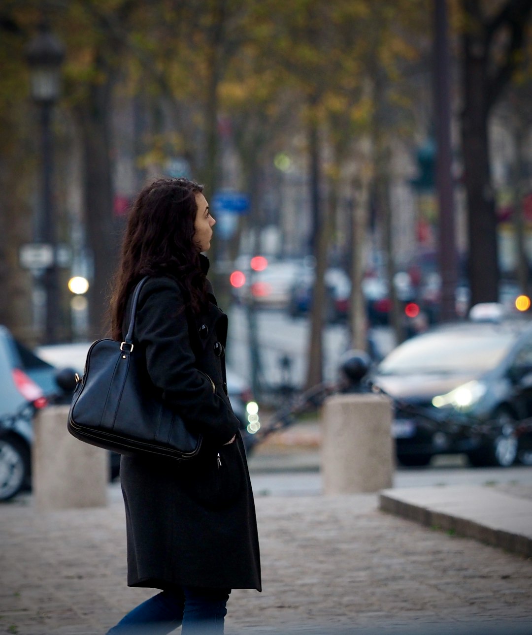 woman in black leather jacket standing on sidewalk during daytime