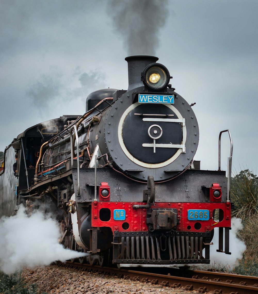 trem preto e vermelho nos trilhos sob o céu nublado durante o dia