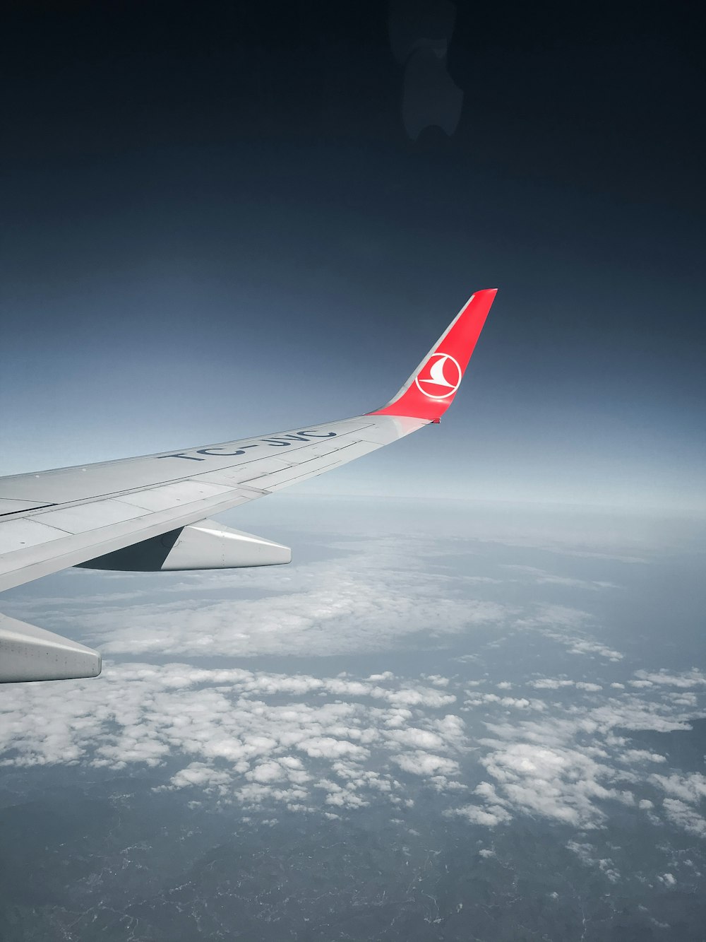 white and red airplane wing under blue sky during daytime