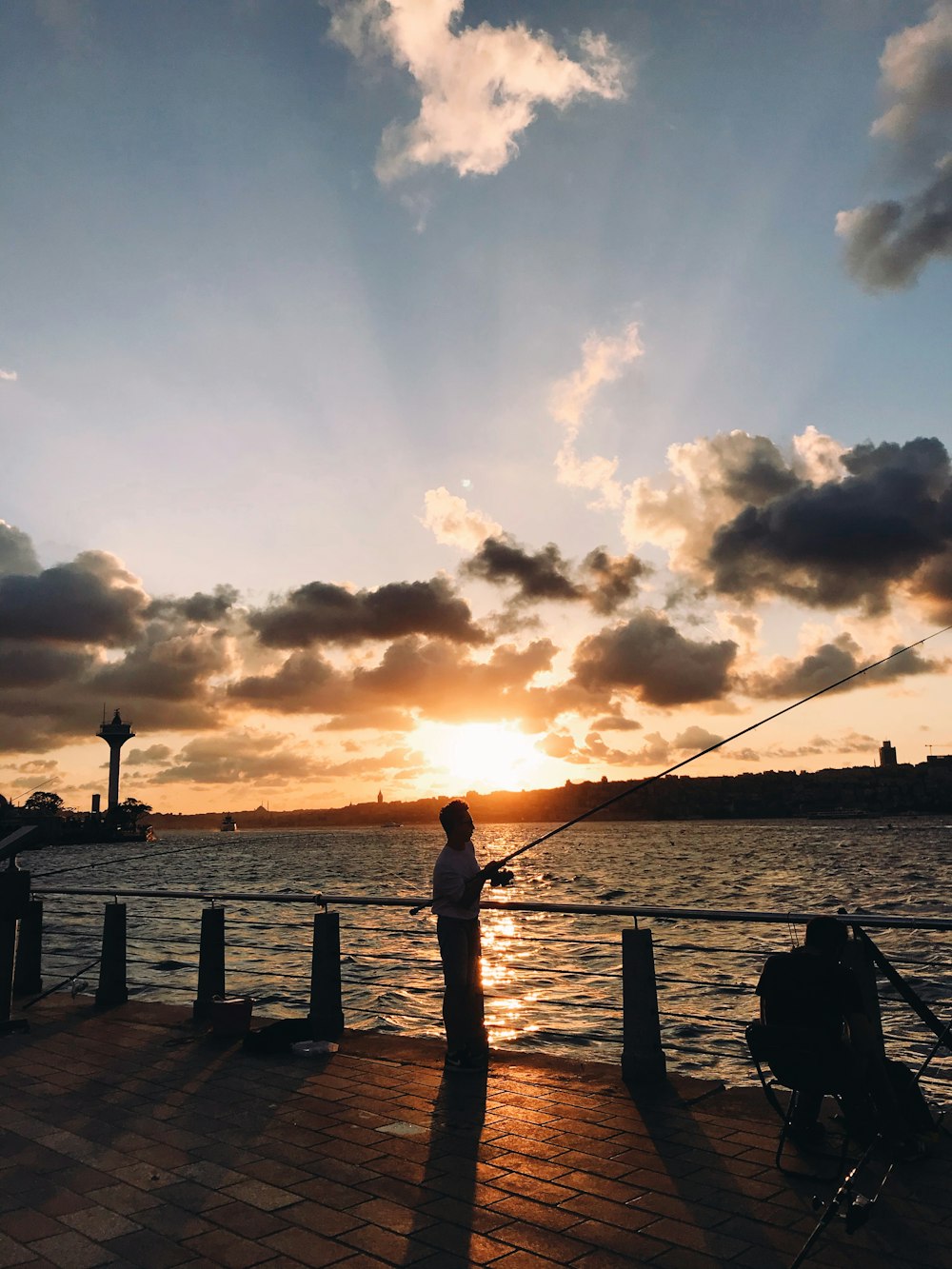 silhouette of person fishing on sea during sunset