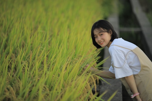 woman in white long sleeve shirt standing on green grass field during daytime
